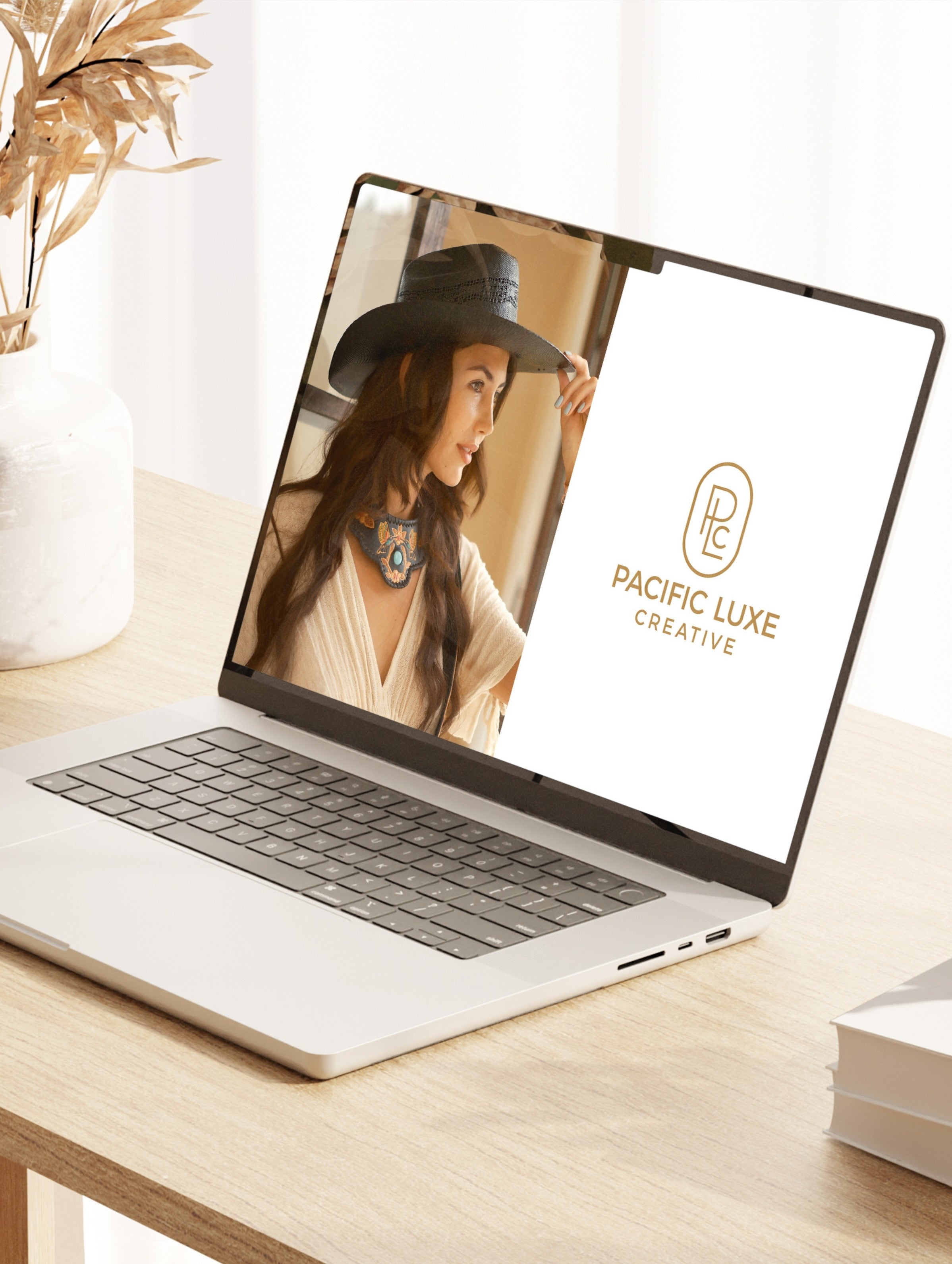 Laptop on a desk displaying a woman's profile with 'Pacific Luxe Creative' logo.