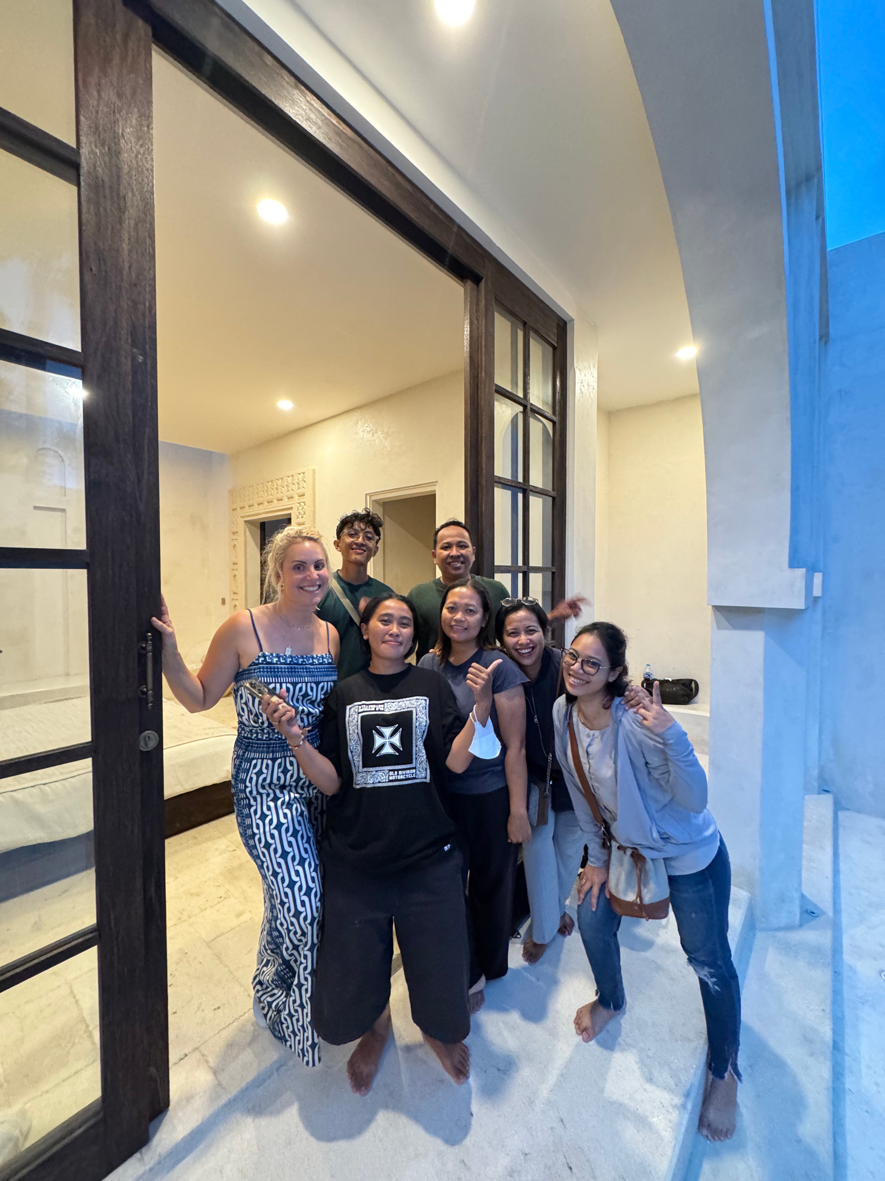 Group of people posing in a modern interior setting with large glass doors.