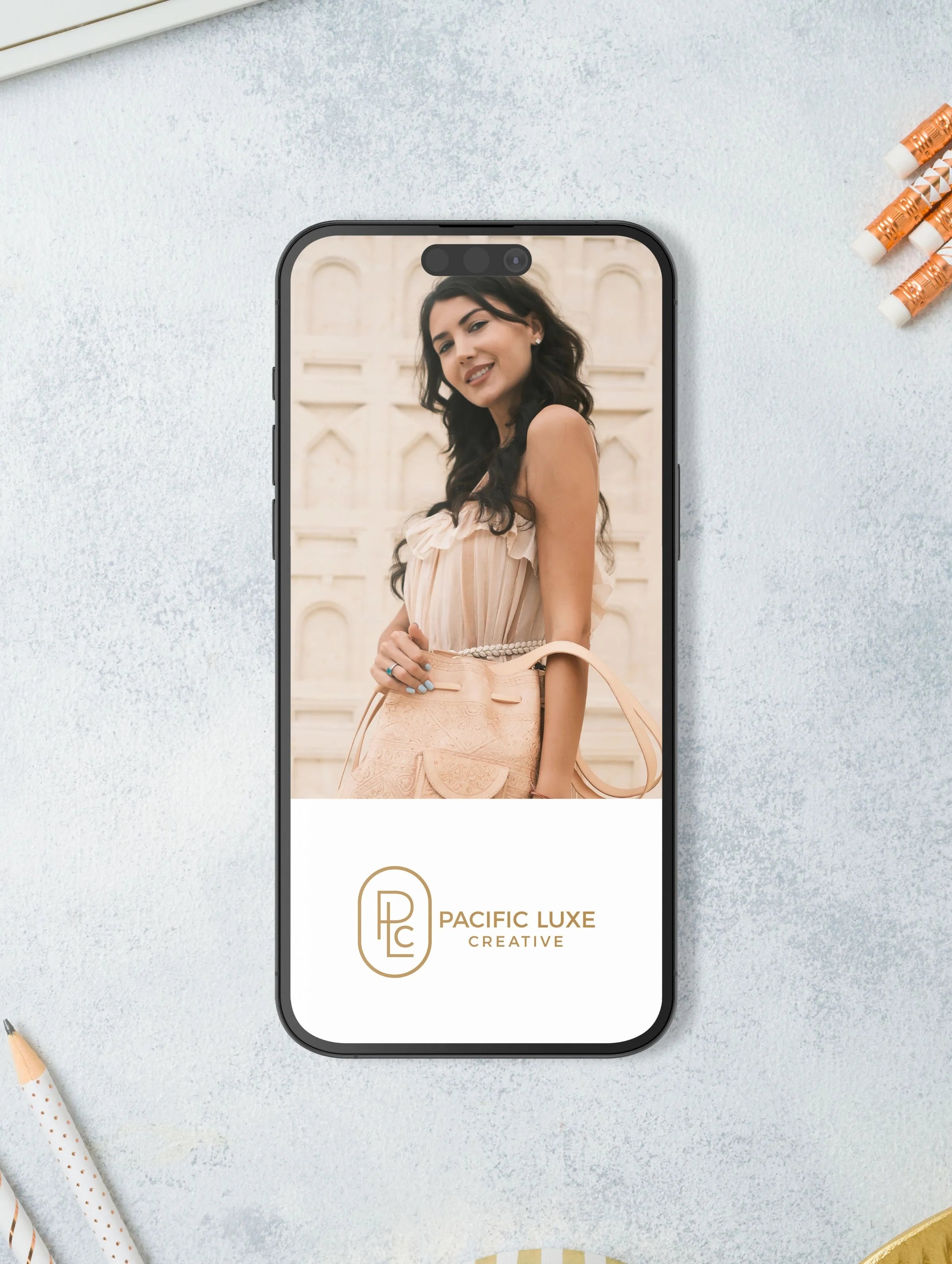 Phone displaying Pacific Luxe Creative logo and portrait of a woman, styled on a light gray surface with a luxe Bali-inspired glow.
