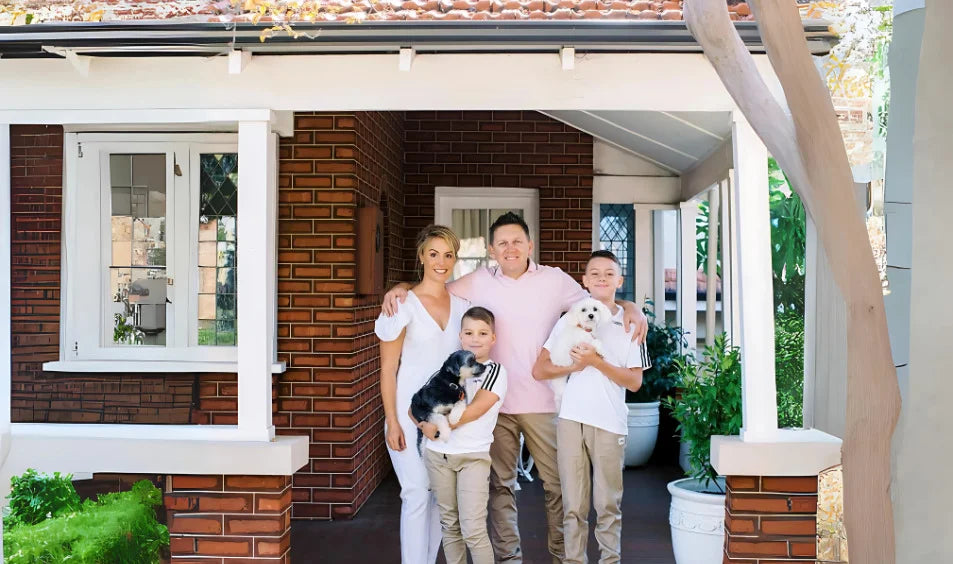 renae huntley and her family of four with two dogs standing on a porch in front of a house