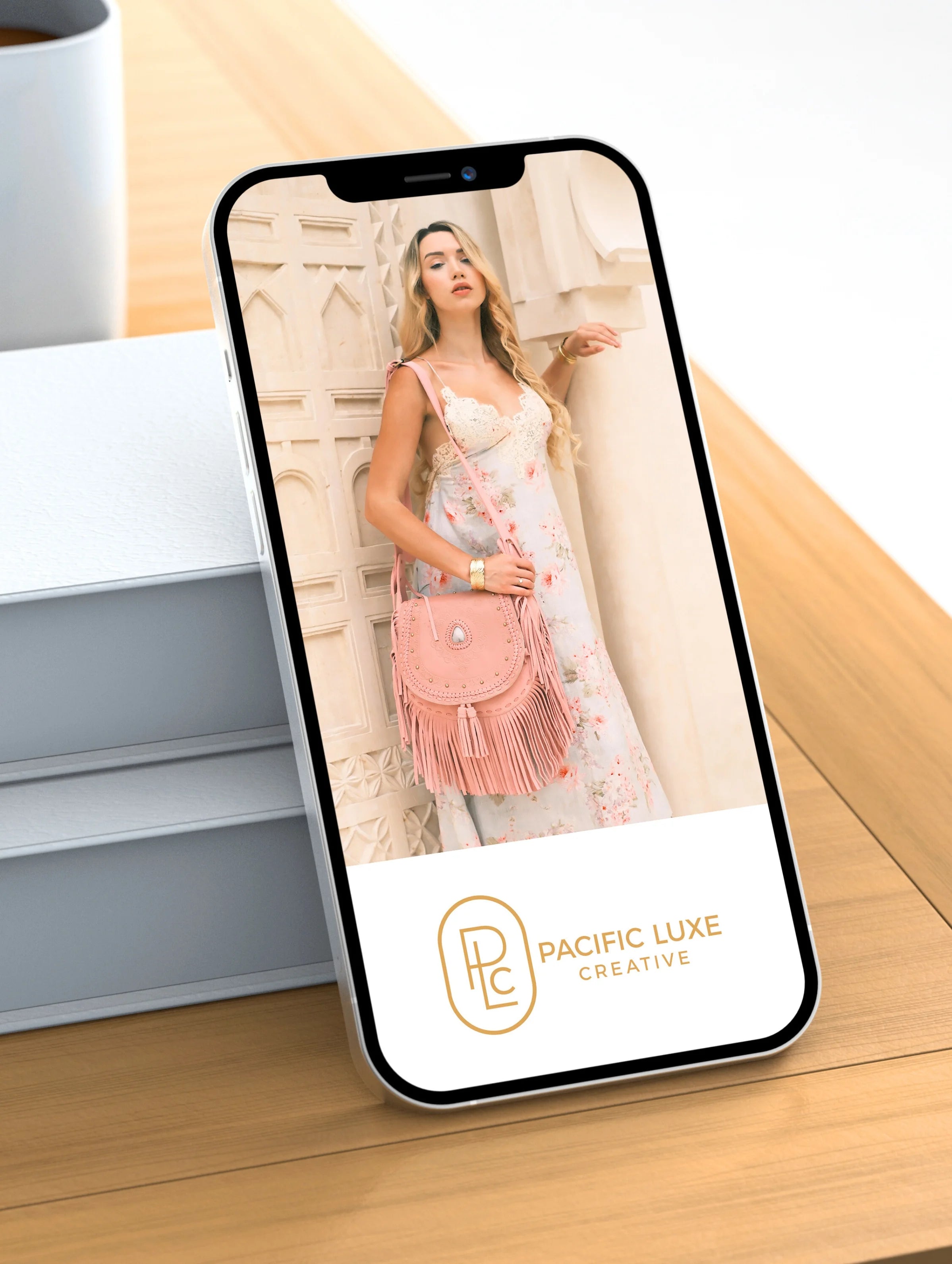 Luxury product photography by Pacific Luxe Creative featuring phone on timber surface with pink handbag imagery and natural Perth glow.