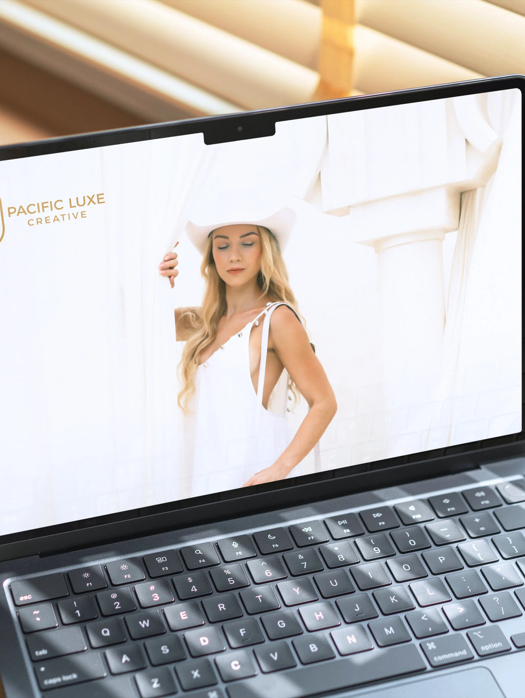Pacific Luxe Creative brand photography laptop displaying a woman in a white dress and hat with a soft Bali-inspired luxury glow.