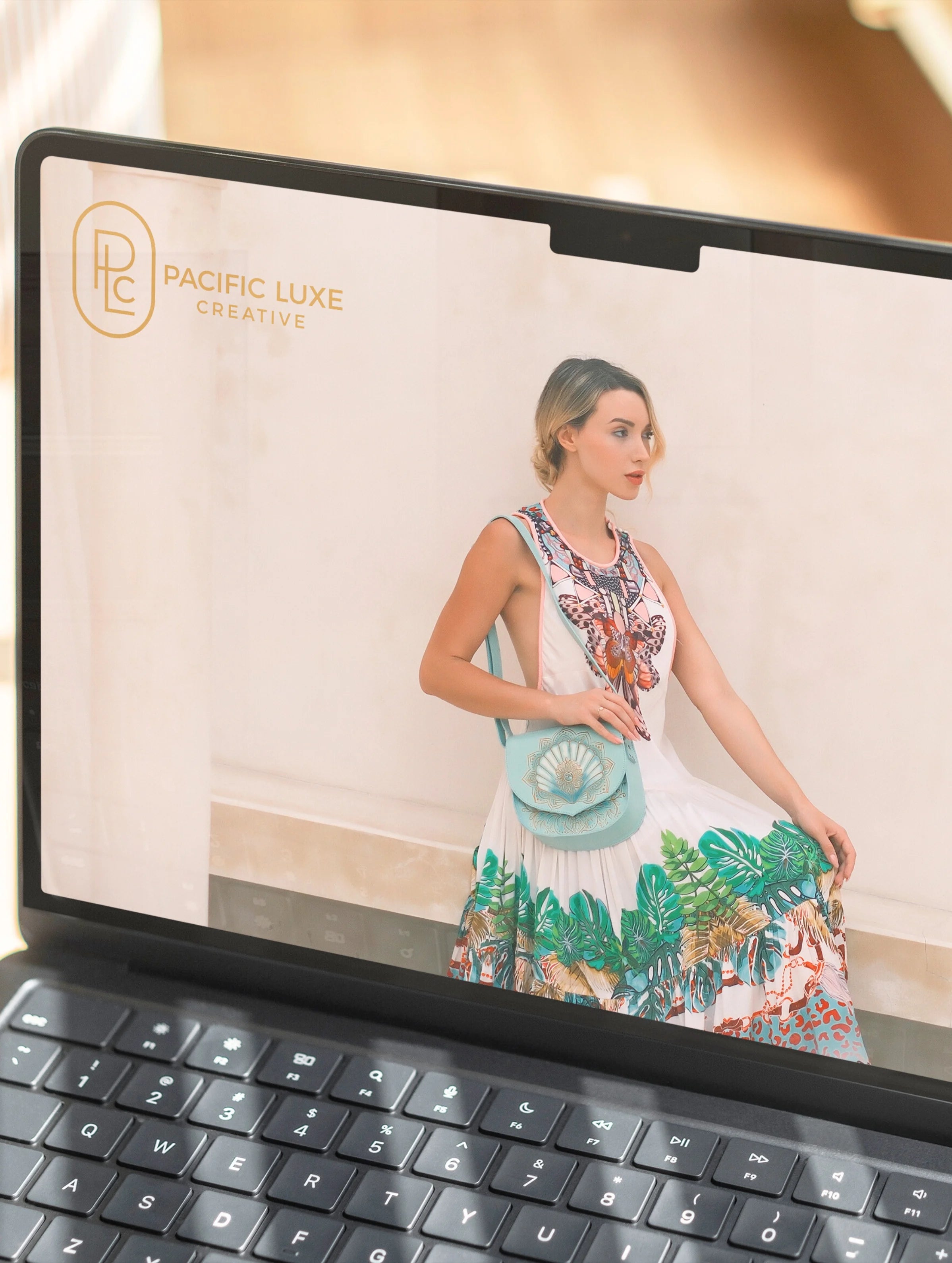 Pacific Luxe Creative brand photography laptop displaying a woman holding a handbag with brand logo, styled with island luxury glow.