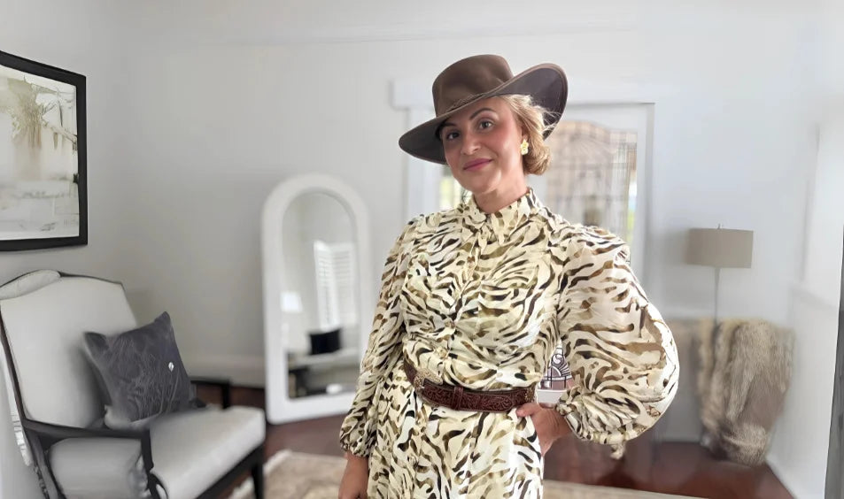 renae huntley wearing a zebra print outfit and hat in a room with furniture and decor.
